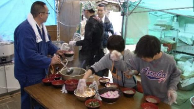 炊き出しを行う男性と子供たちの様子